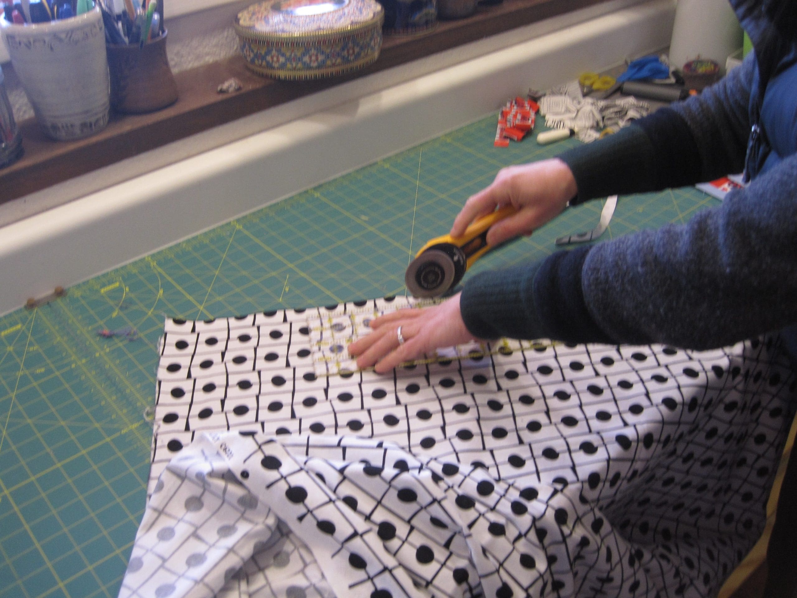 Because I am working with a print, I must continually be slightly adjusting my ruler. I am using the 1/4" so that when I stitch I will have a 1/4" seam along the edge of the print. This is results in an even quarter of an inch seam in relationship to the black line on the fabric. 